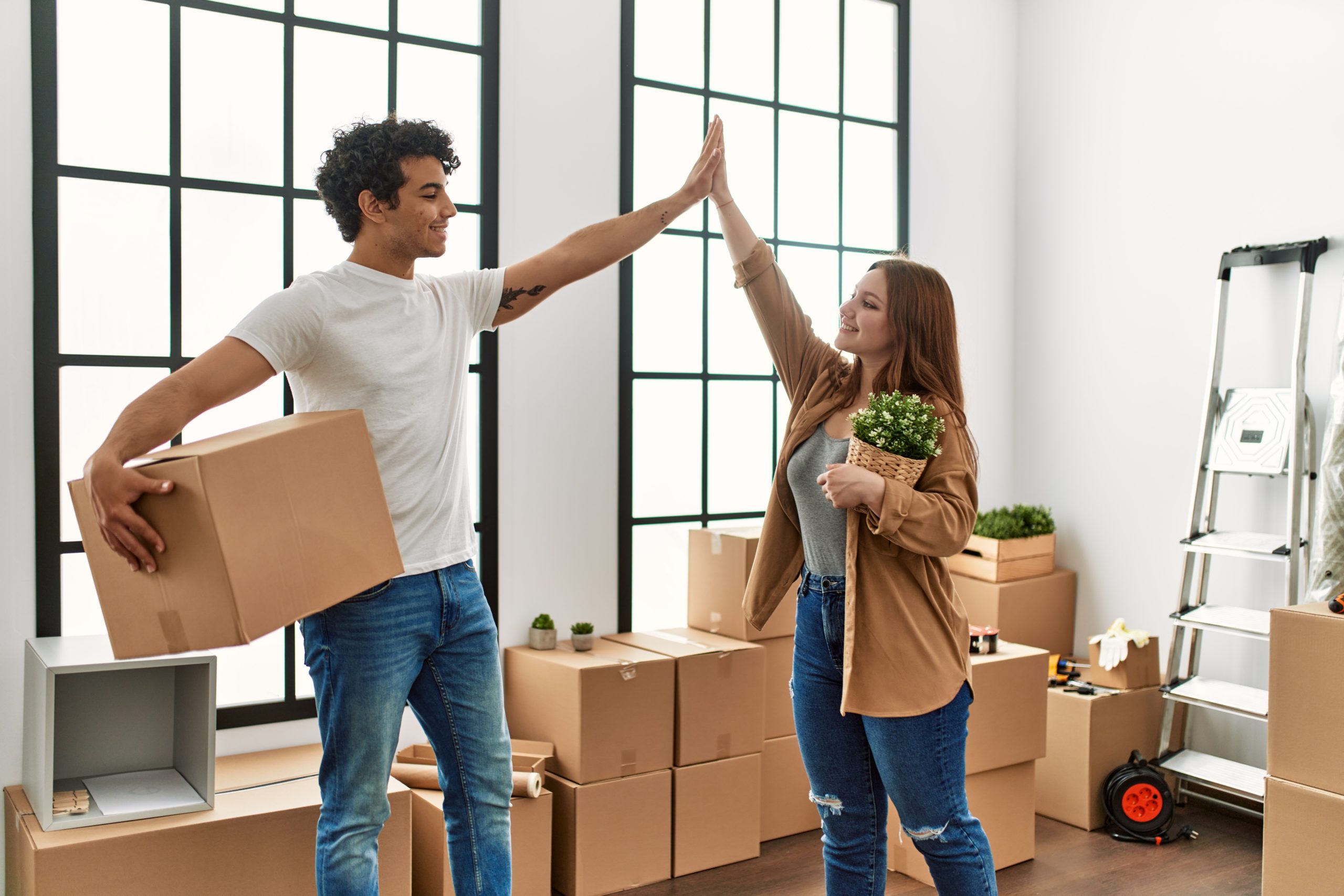 Jeune couple avec cartons tapent mains heureux du déménagement